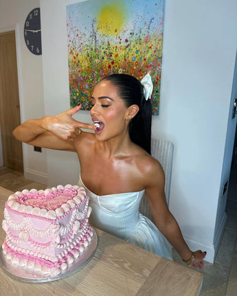 A woman taking a bite of a pink heart shaped vintage cake at home