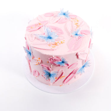 Free From Butterfly Cake with pink buttercream, gold and pearl sprinkles and blue sugar butterflies