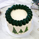Christmas Tree Cake with dark green piped buttercream trees, with festive decorations