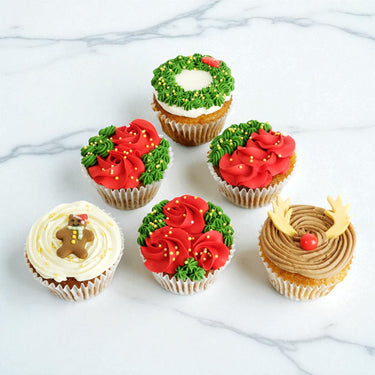 Six Christmas Cupcakes on marble, decorated as reindeer, wreaths and gingerbread