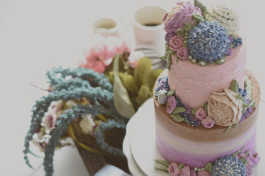 Two tier floral cake with piped buttercream flowers in pink, purple and blue