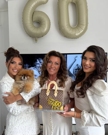 Three women celebrating a 60th birthday with a designer handbag cake