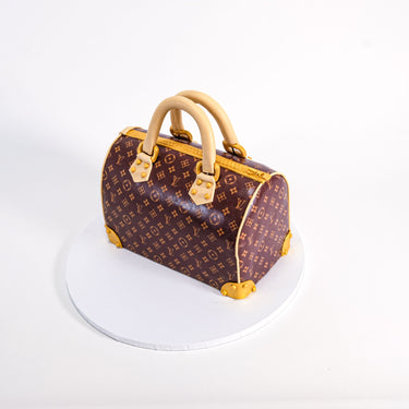 Handbag Cake with a monogram print, gold details and handles, on a cake board