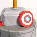 Grey fondant Marvel Avengers Cake topped with Thor's hammer and Captain America's shield