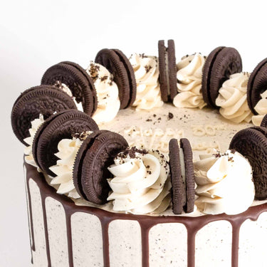 Oreo Cake with chocolate drip, vanilla swirls and Oreo biscuits, with a piped happy birthday message