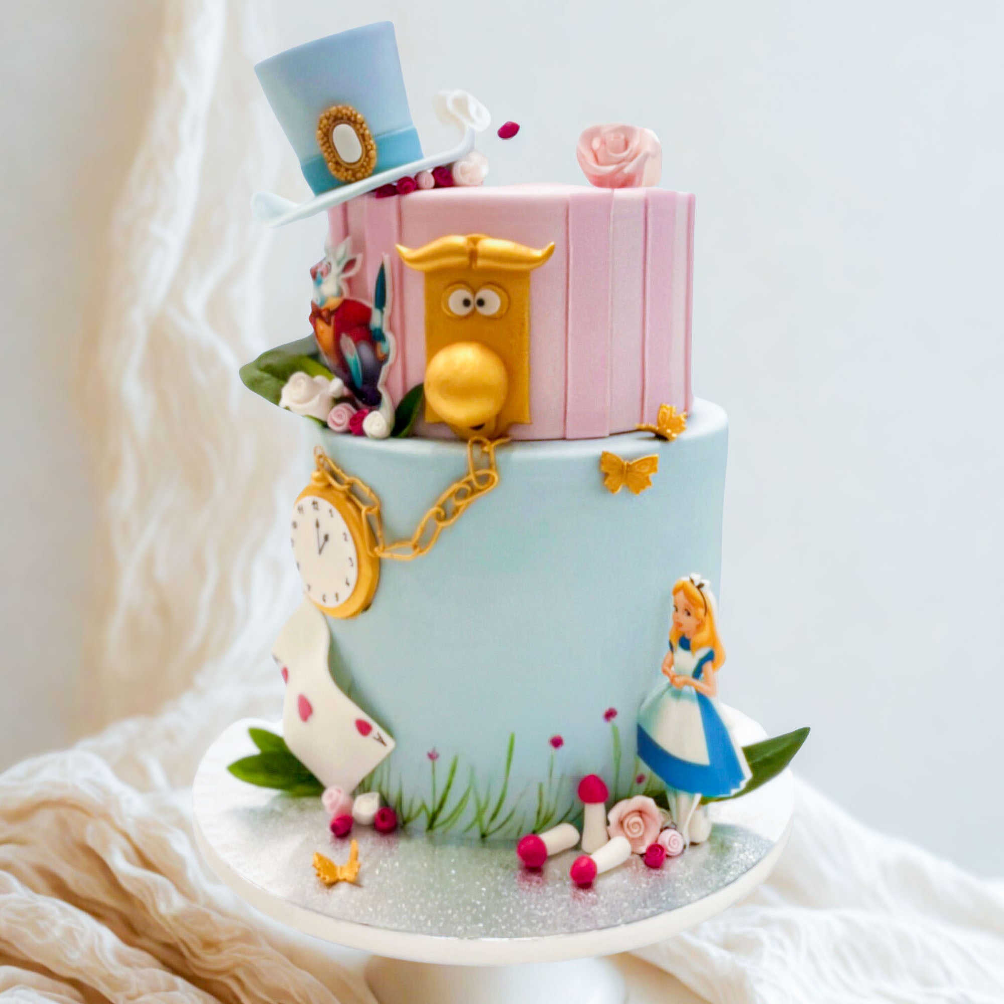 Alice in Wonderland two tier cake with a top hat, clock and Alice figure