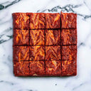 16 Red Velvet Brownies with cream cheese swirls, on marble