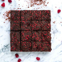 Raspberry and Amaretti Brownies with chocolate drizzle and freeze dried raspberries, on marble