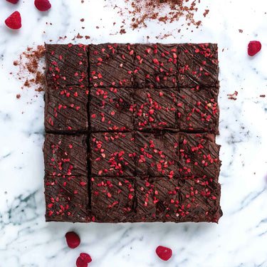 Raspberry and Amaretti Brownies with chocolate drizzle and freeze dried raspberries, on marble