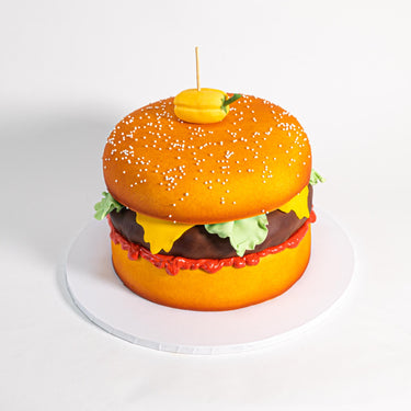 Cheeseburger Cake with sponge buns, chocolate patty and fondant toppings, finished with a fondant pepper on a skewer