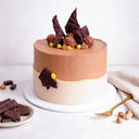 Ferrero Rocher Cake topped with chocolate shards, Ferrero Rocher and hazelnuts, with dark chocolate and a gold fork