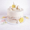 Semi naked Lemon Drizzle Cake with white macarons, meringue kisses, dried grasses and lemon slices