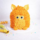 Gluten friendly Free From Furby Cake with orange buttercream fur and fondant ears, eyes, nose and feet