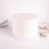 Undecorated Cake with smooth white buttercream, next to a bowl of sprinkles