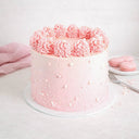 Ombré Cake with pink buttercream, piped rosettes and sugar pearls, next to a plate of pink macarons