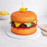 Cheeseburger Cake made to look like a burger, with sponge buns, a chocolate patty and fondant lettuce and cheese