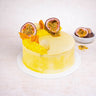 Mini White Chocolate Passionfruit Cake with yellow buttercream, passionfruit and dried mango, next to passionfruit halves