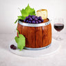 Free From Wine Barrel Cake with fondant grapes, cheese and vine leaves, next to a glass of red wine
