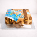 Suitcase Cake designed as a vintage travel trunk with fondant straps, buckles, a world map and travel stickers