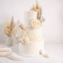 Boho Wedding Cake with dried grasses, pampas, palm leaves, a cream rose, eucalyptus and white macarons