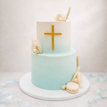 Two tier christening cake with a gold cross and seashells