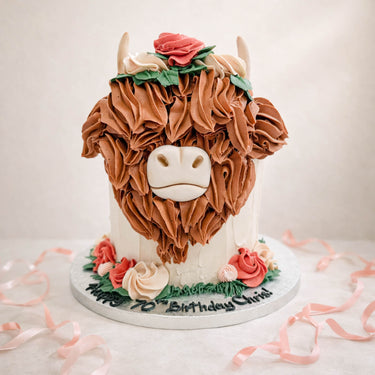 Highland cow cake with piped buttercream fur and pink flowers