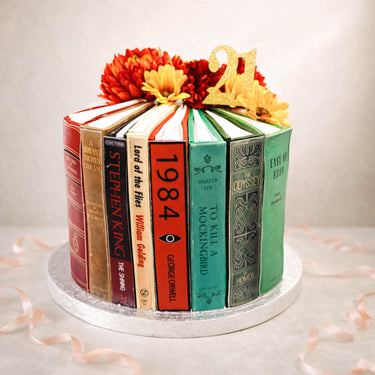 Book spine cake with classic novels and flowers on top