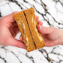Hands holding a thick Almond Croissant Cookie topped with flaked almonds