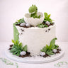 Free From Baby Dino Cake with textured buttercream, edible soil, sweet pebbles and a dinosaur hatching from an egg