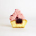 Raspberry Cupcake cut in half, showing vanilla sponge with a raspberry coulis centre