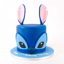 Stitch Cake shaped like the character, with fondant details and a birthday message on a blue board