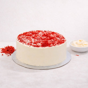 Red Velvet Cake with smooth white buttercream and red velvet crumbs on a silver board