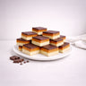 Wholesale Millionaire Slice: Three-layer bars with shortbread base, caramel middle, and chocolate top on a plate, featuring extra chocolate pieces and chips.