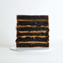 Free From Triple Chocolate Cake with chocolate drip and handmade chocolates on a white cake board