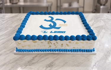 Rectangular white corporate cake with LEMO 30 years anniversary logo, blue piped border and gold leaf on the sides
