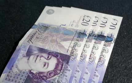 Fanned out British £20 polymer banknotes on a dark surface, symbolizing premium quality and care akin to Harry Batten's bespoke bakery creations.