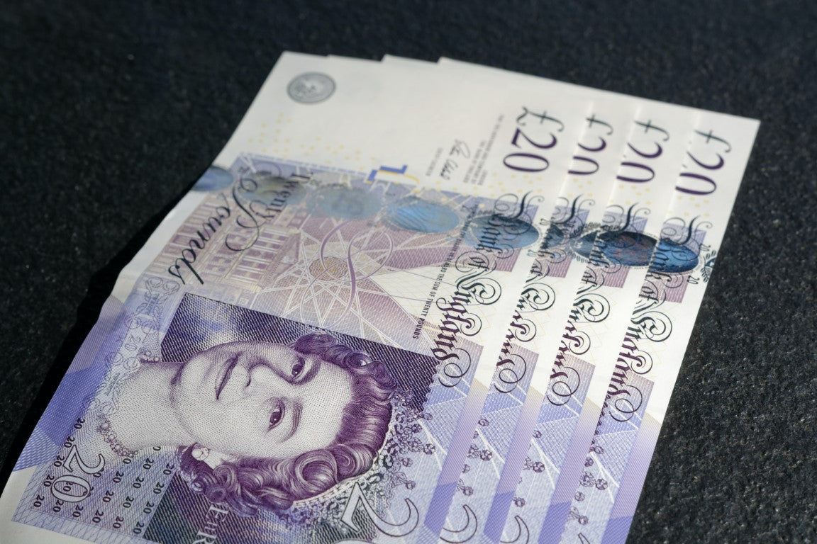 Fanned out British £20 polymer banknotes on a dark surface, symbolizing premium quality and care akin to Harry Batten's bespoke bakery creations.