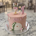 Pale pink fairy first birthday cake with a sugar fairy, number one, white daisies, butterflies, toadstools and a fairy door
