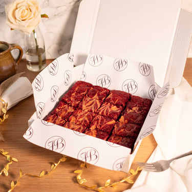 Box of Red Velvet Brownies with a napkin, fork and a rose on a wooden table