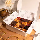 Box of assorted brownies and blondies with a rose and a mug on a wooden table