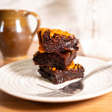 Three brownies drizzled with caramel on a plate