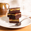 Three layered brownie bars with a chocolate base, custard layer and ganache
