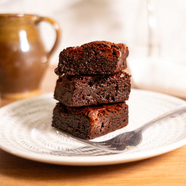 Stack of three fudgy brownies on a patterned plate with a fork