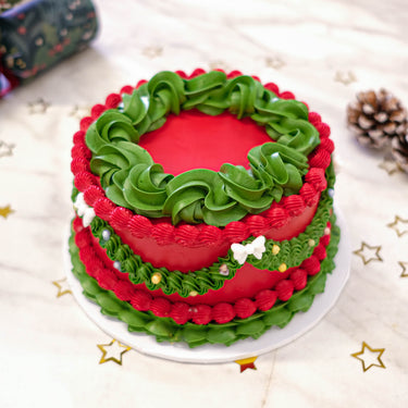 Red Frilly Christmas Cake with green piping and sugar pearls, with pine cones and gold stars