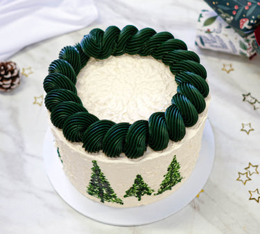 Christmas Tree Cake with dark green piped buttercream trees, with festive decorations