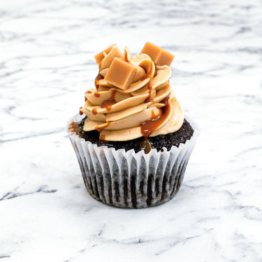 Chocolate Caramel Cupcake with caramel buttercream, caramel drizzle and fudge pieces, on marble