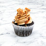 Chocolate Caramel Cupcake with caramel buttercream, caramel drizzle and fudge pieces, on marble