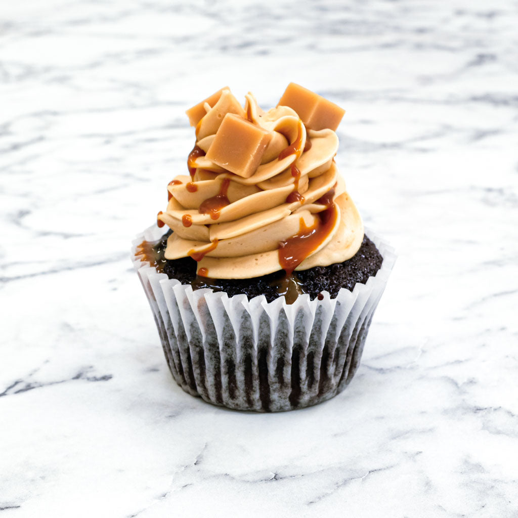 Chocolate Caramel Cupcake with caramel buttercream, caramel drizzle and fudge pieces, on marble