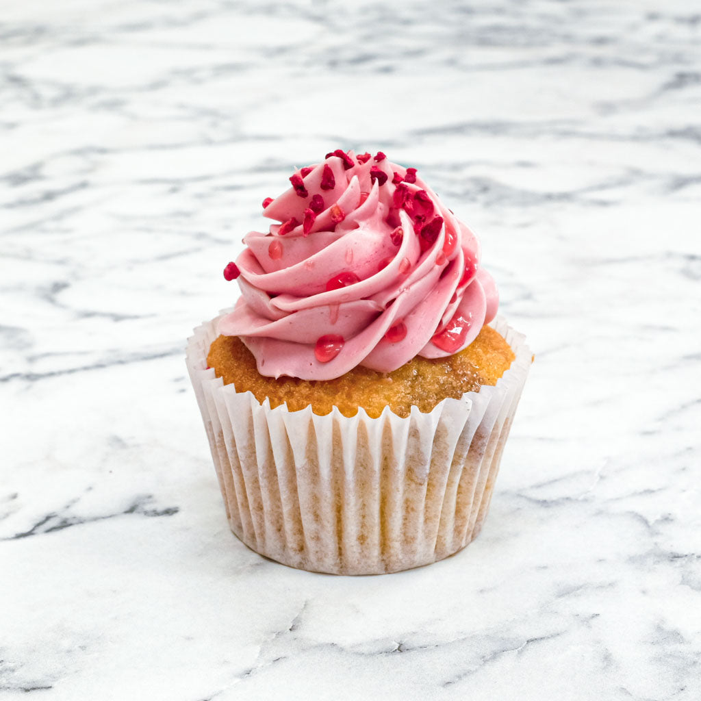 Raspberry Cupcake with pink buttercream, raspberry drizzle and freeze dried raspberries, on marble