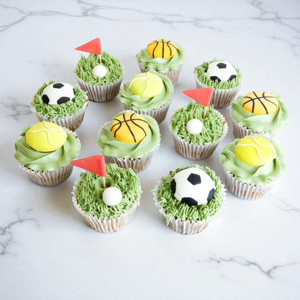 12 Sports Cupcakes with green buttercream grass and fondant footballs, basketballs, tennis balls and golf flags